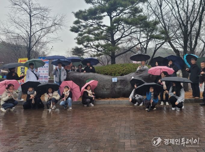 학생들이 비가 오는 날씨 속에서도 우산을 받쳐 든 채 우포늪 생태에 대한 설명을 듣고 있다.